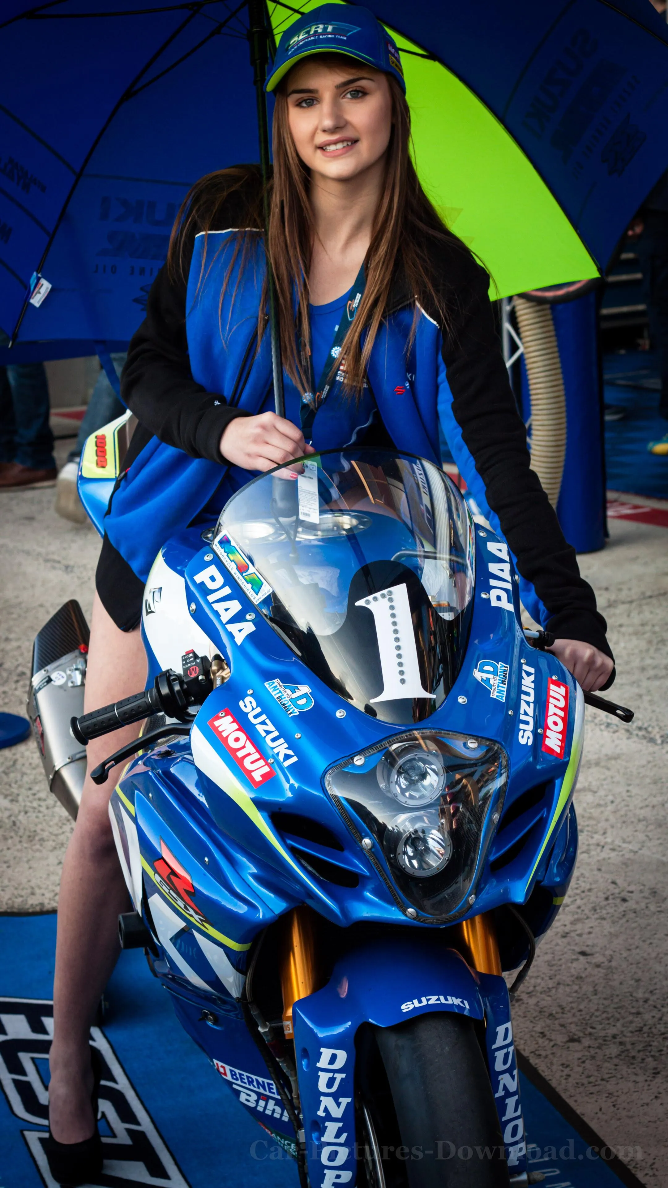 Woman in Racing Gear Sitting on a Motorbike with an Umbrella
