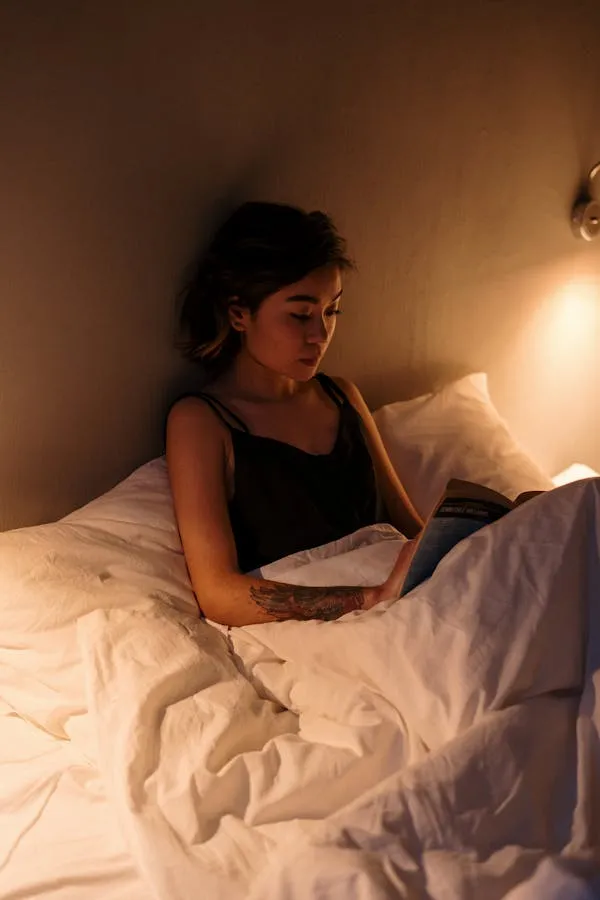 Woman Reading a Book in Bed Under a Warm Ambient Light Image