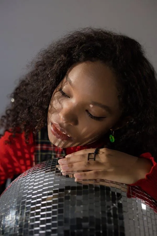 Woman in a Red Dress Hugging a Disco Ball in Soft Lighting