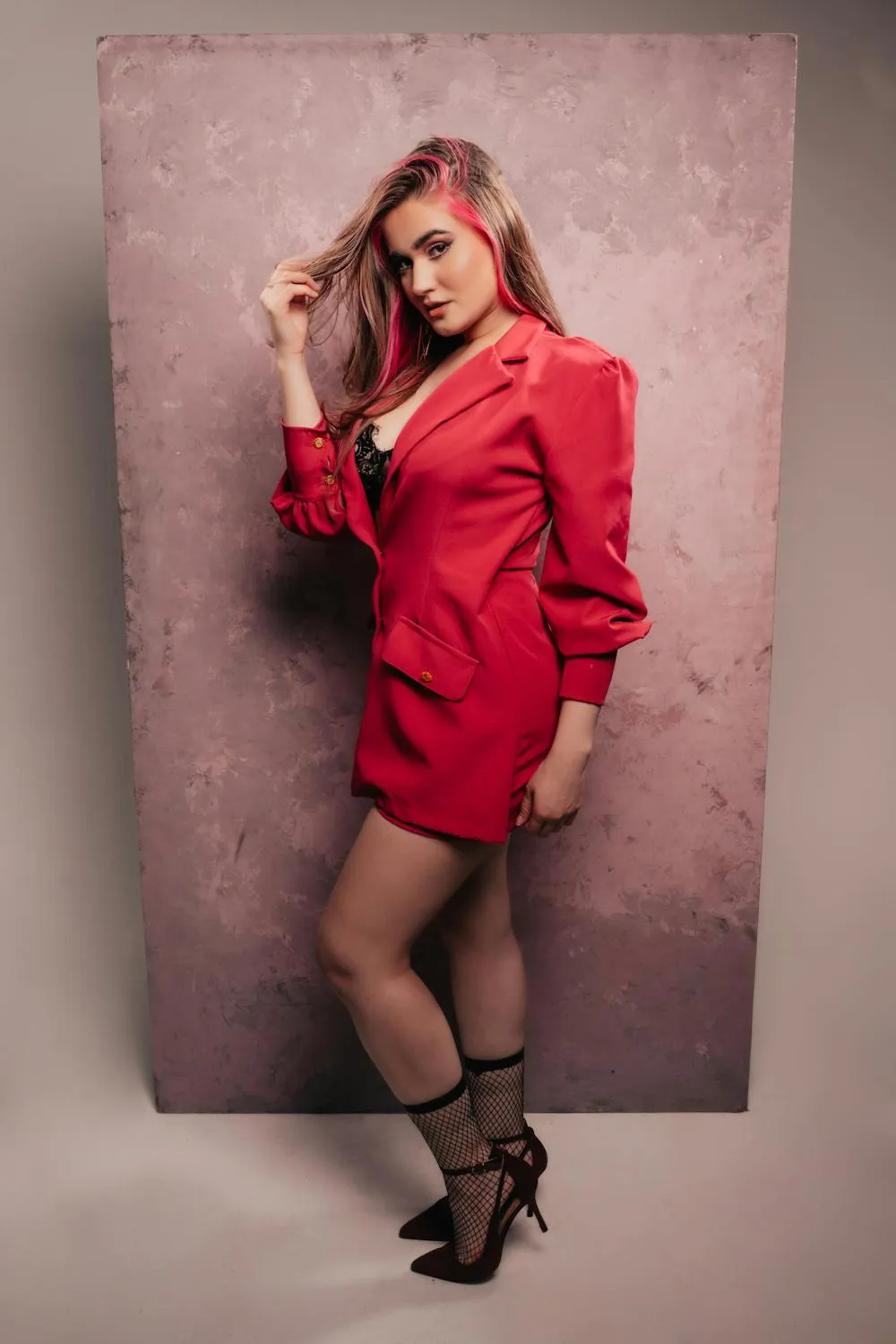 Woman in Red Dress Posing Against Textured Pink Studio Wall