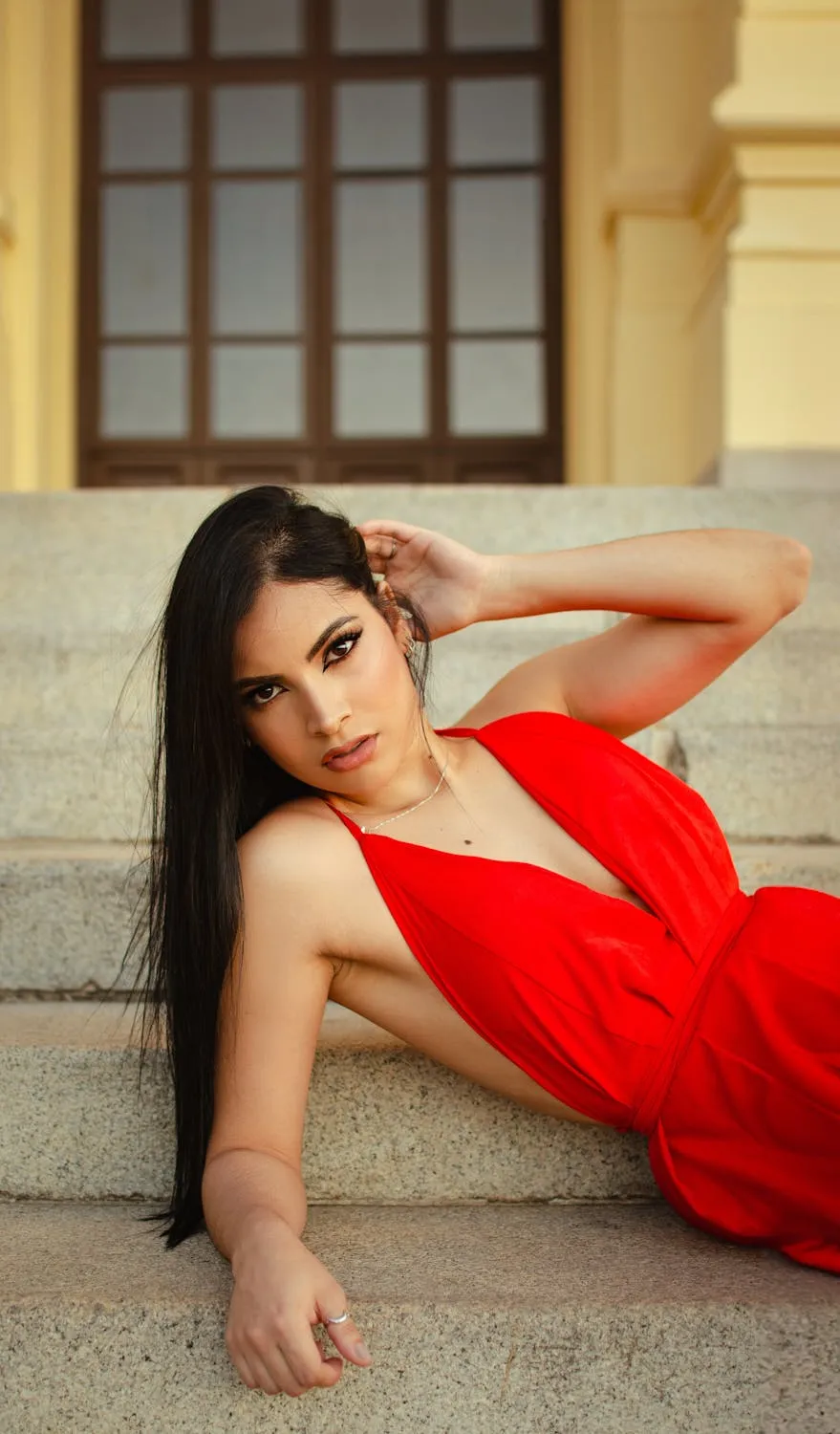 Woman in Red Dress Posing with One Hand on Her Head Outdoors