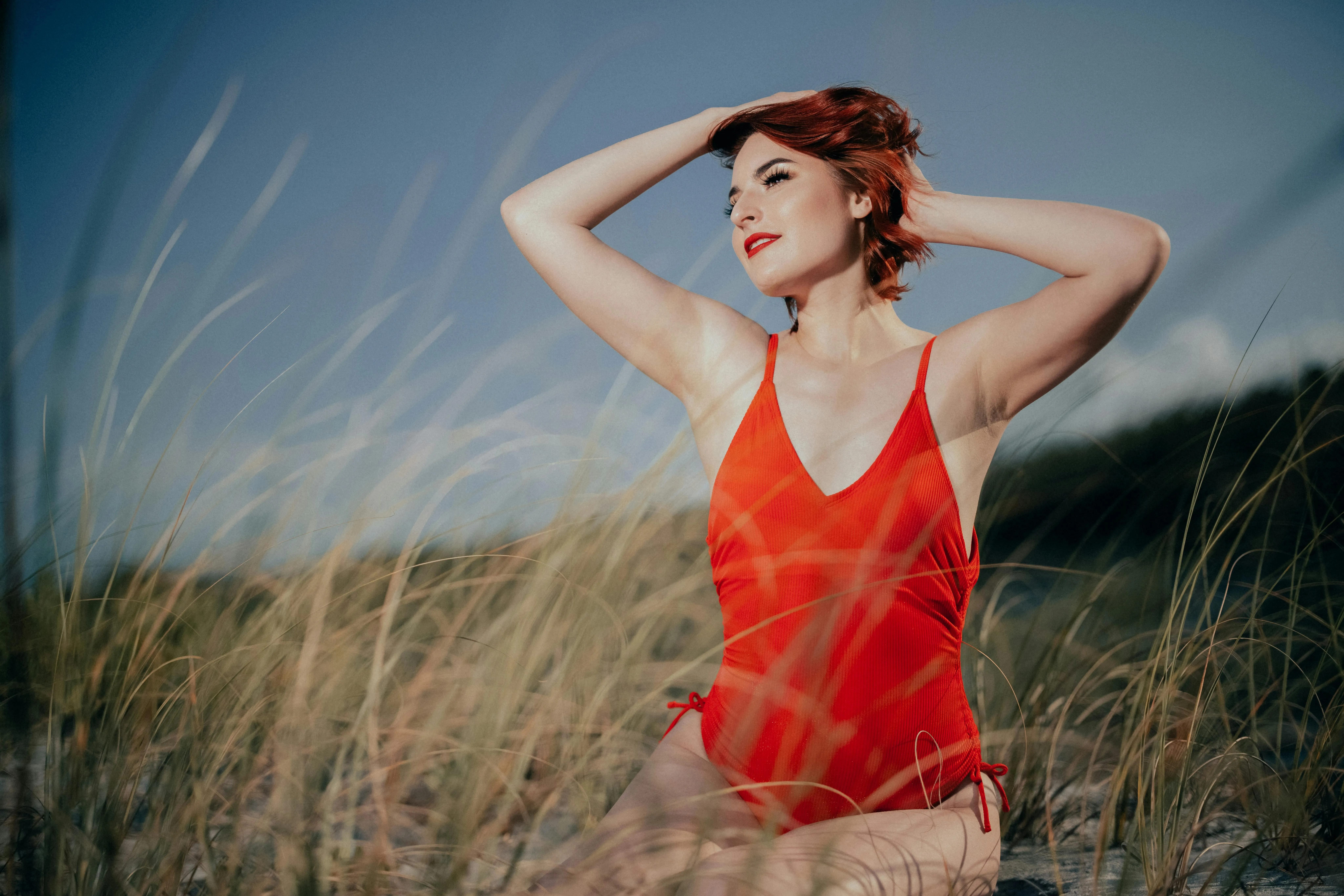Woman in a Red Dress Posing Outdoors in a Tall Grassy Field
