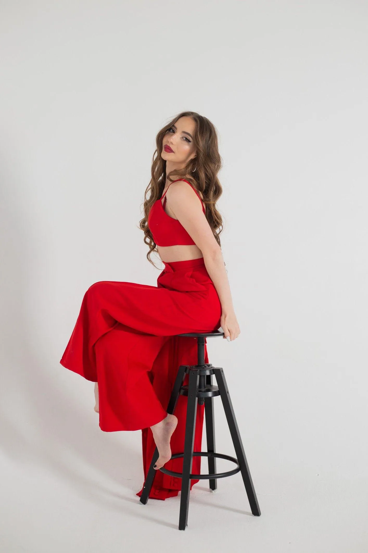Woman in a Red Dress Sitting Gracefully on a Black Stool