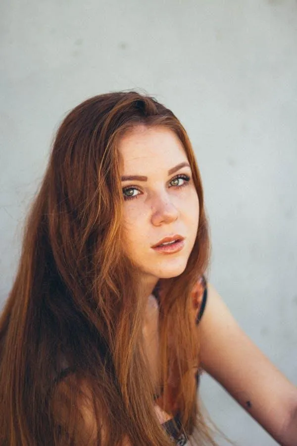 Woman with Red Hair Looking Up While Sitting in Soft Light