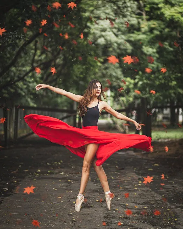 Woman in Red Skirt Dancing Joyfully with Falling Leaves