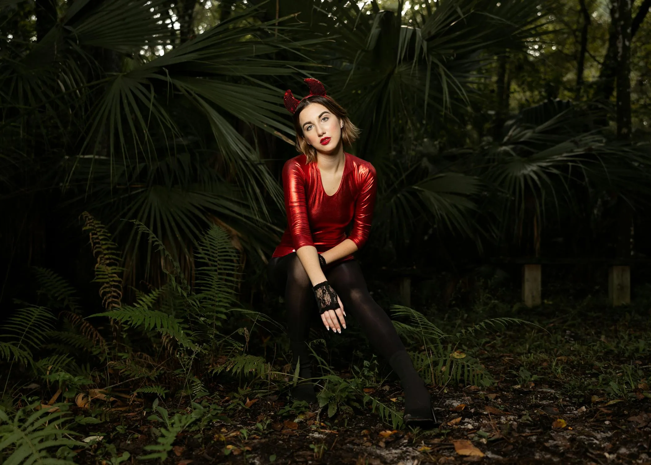 Woman in a Red Top Sitting on a Log in a Lush Green Forest