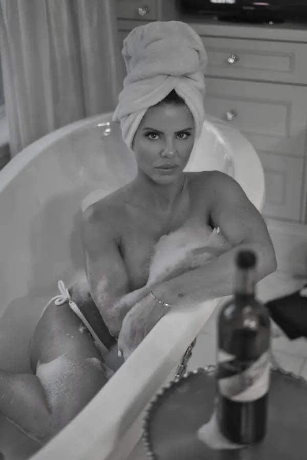 Woman Relaxing in a Bathtub with a Towel and a Wine Bottle
