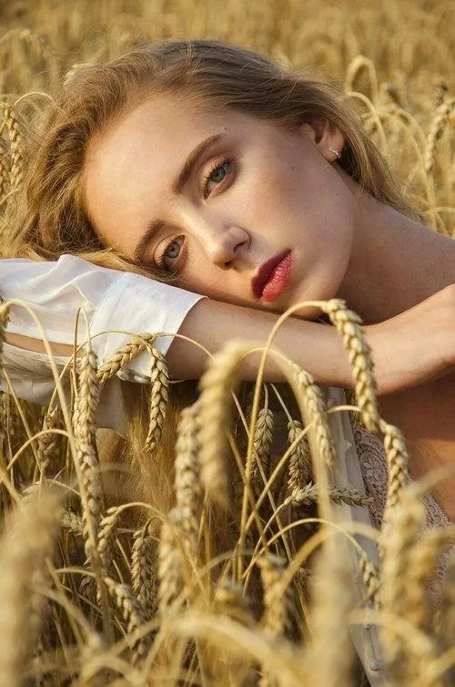 Woman Resting in a Golden Field with a Dreamy Expression