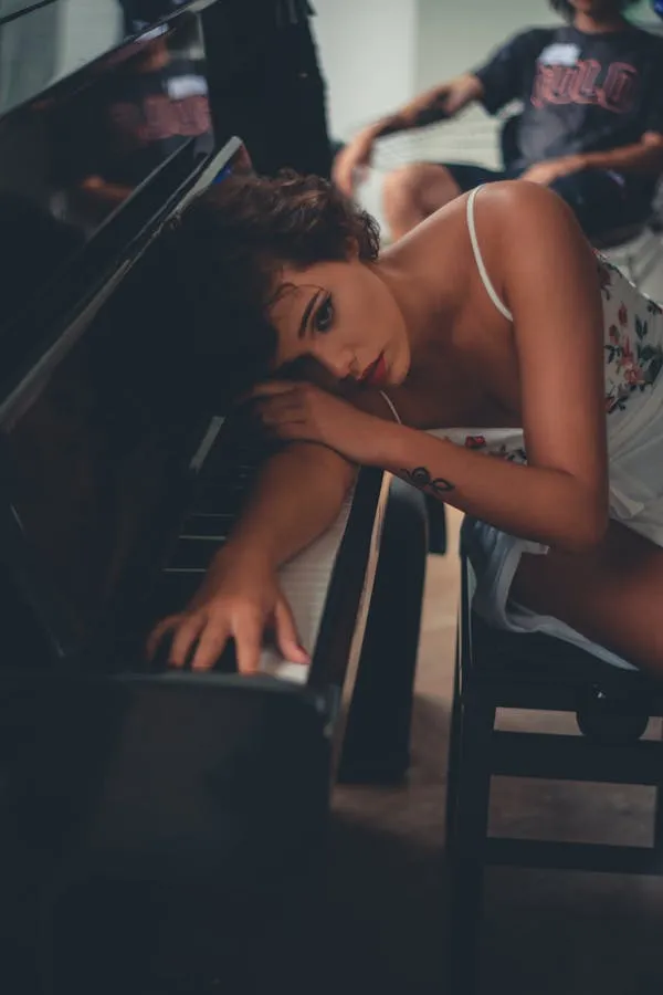 Woman Resting on a Piano with a Calm and Thoughtful Look