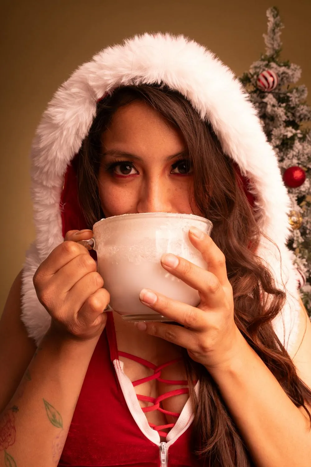Woman in a Santa Outfit Holding a Mug During Christmas Time
