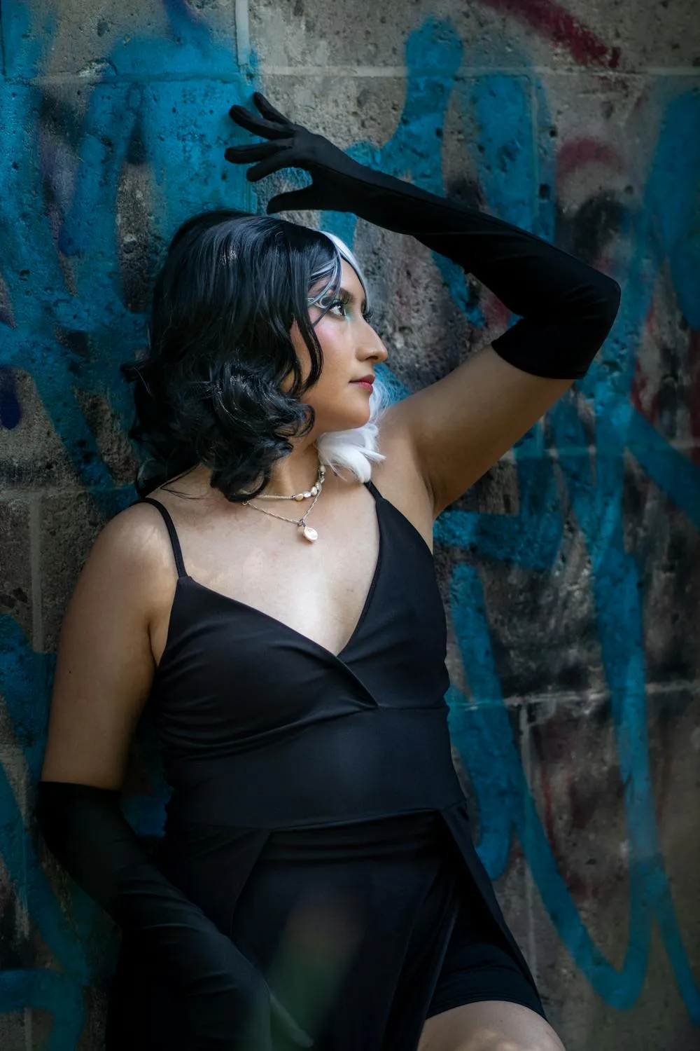Woman in a Sheer Black Dress Posing Against an Urban Wall