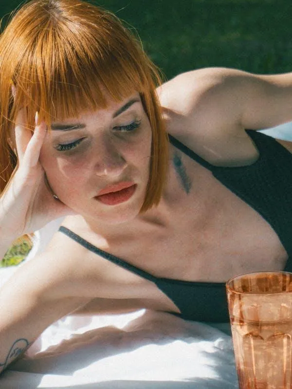 Woman with a Short Red Hair Resting Her Head on Her Hand