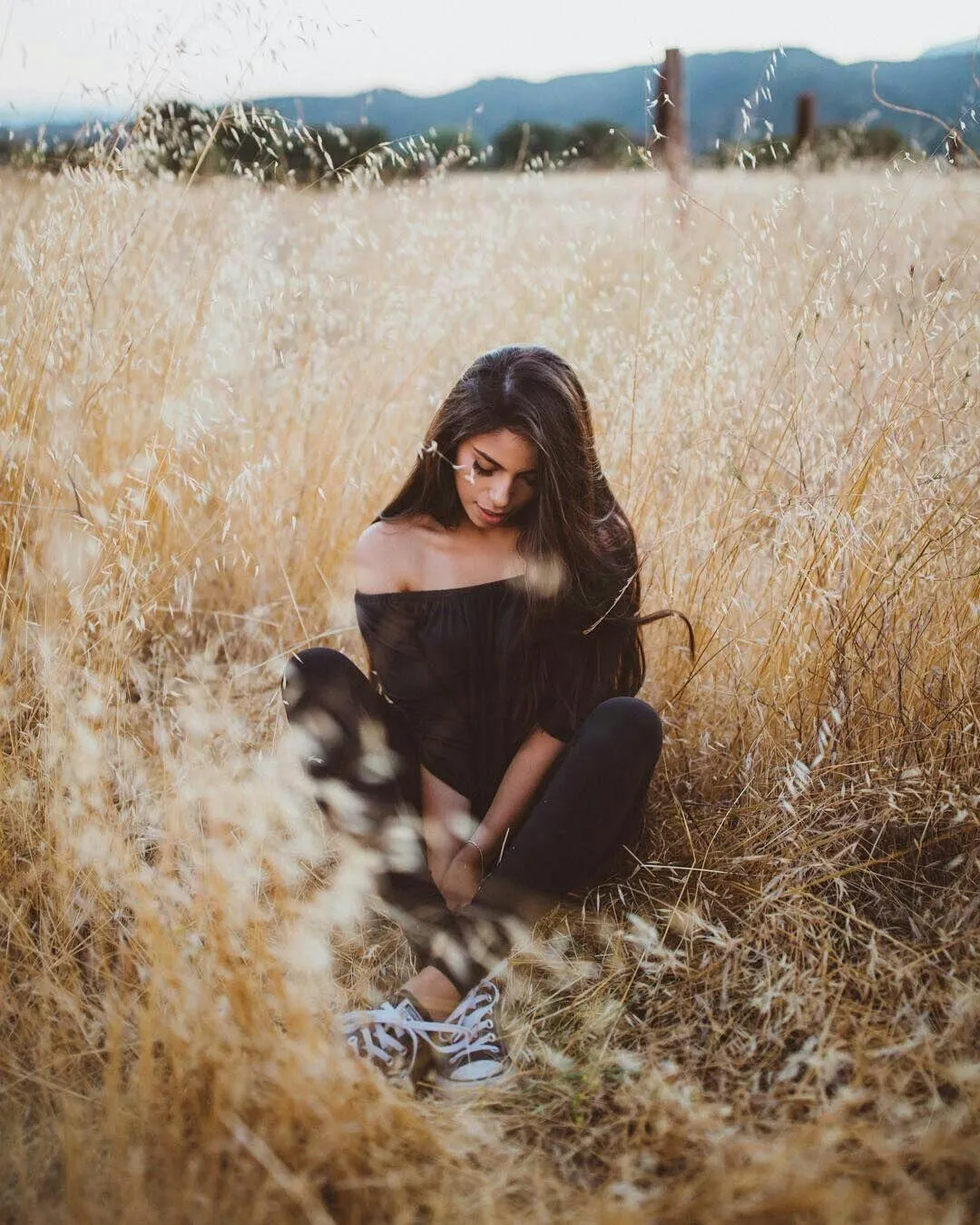 Woman Sitting Alone in a Dry Grass Field At Dusk Wallpaper