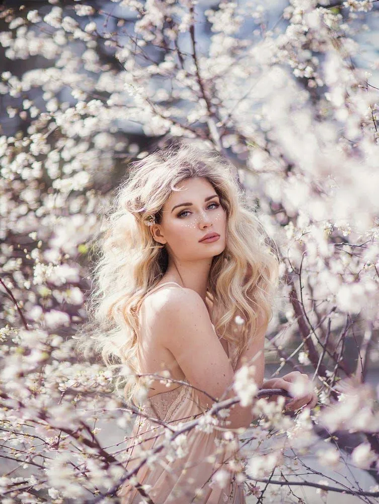 Woman Sitting Among Blooming Trees in a Soft Spring Light