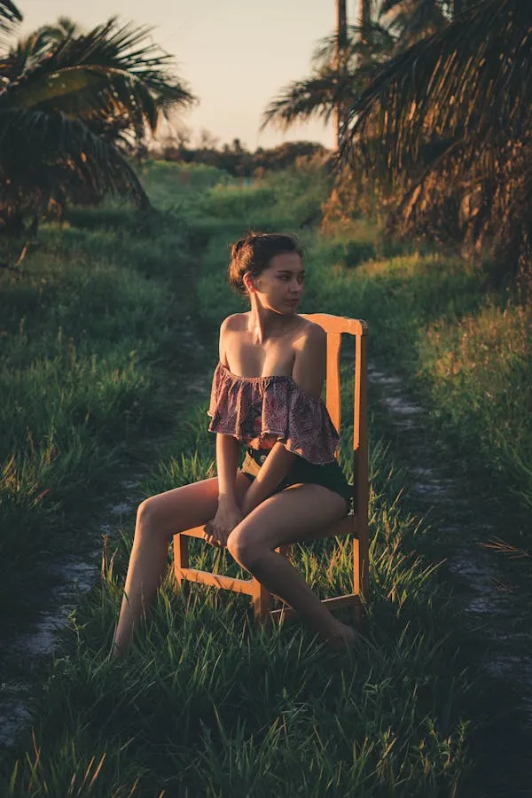 Woman Sitting on a Chair in a Field At Golden Hour Wallpaper