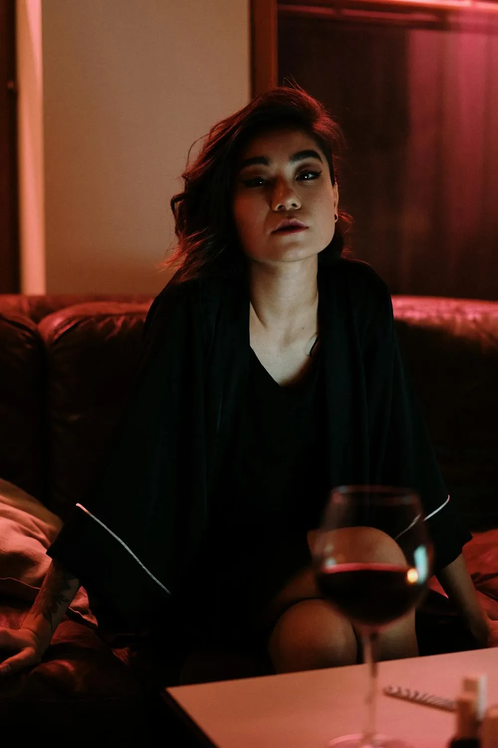 Woman Sitting in Dim Room Holding a Glass of Wine Wallpaper