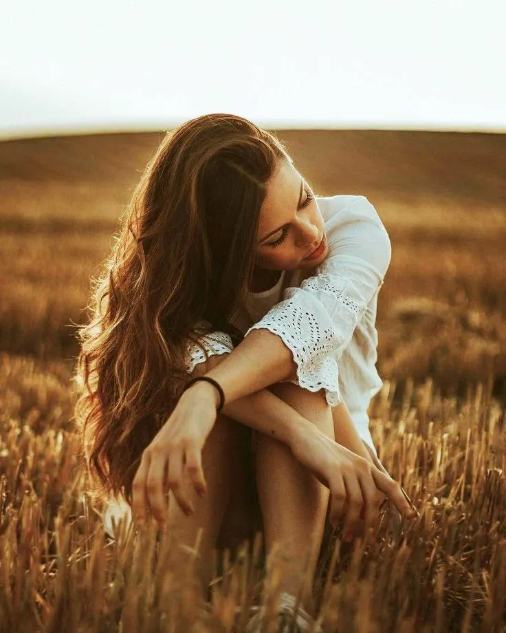 Woman Sitting in a Field with Sunlight and Peaceful Vibes