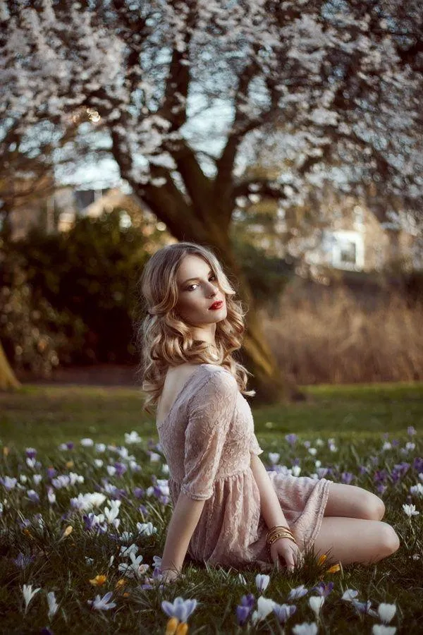 Woman Sitting in a Grassy Field Surrounded by Flowers Image