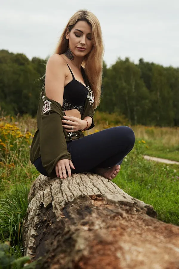 Woman Sitting on a Log in Nature with a Forest Background