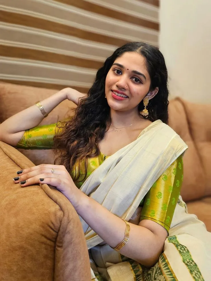 Woman sitting on a sofa wearing a traditional Kerala dress