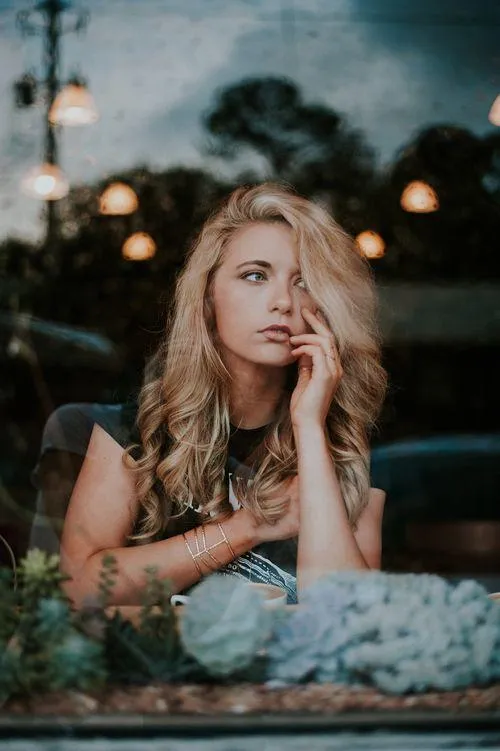 Woman Sitting Outdoors At a Table with Thoughtful Expression