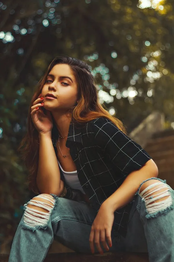 Woman Sitting Outdoors with Ripped Jeans and a Plaid Shirt