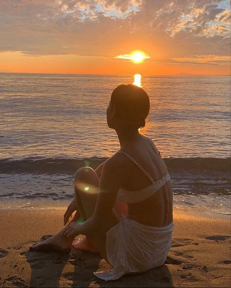 Woman Sitting Peacefully on the Beach Watching the Sunset