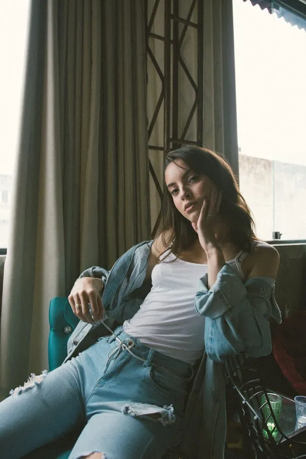 Woman Sitting Relaxed in a Denim Outfit Near a Window Image