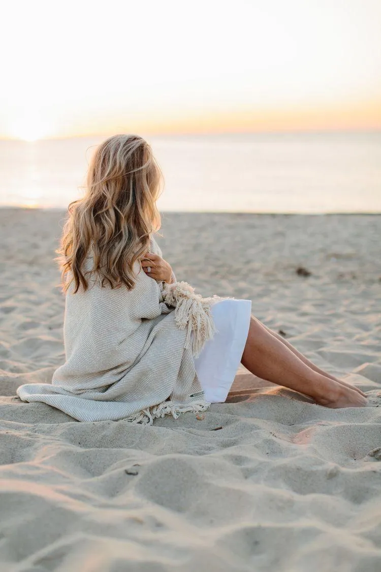 Woman Sitting on a Sandy Beach Watching the Sunset Horizon