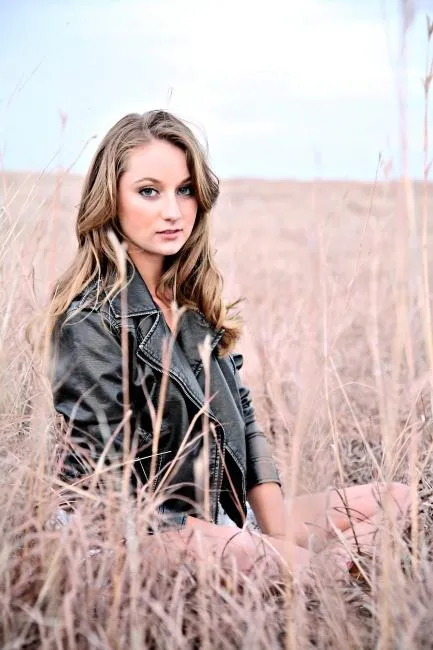 Woman Sitting in Tall Dry Grass Wearing a Leather Jacket