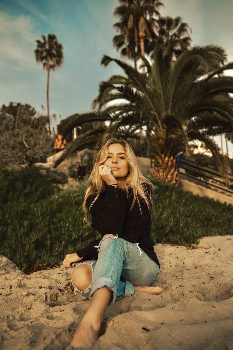 Woman Sitting on the Ground Near Palm Trees and Blue Skies