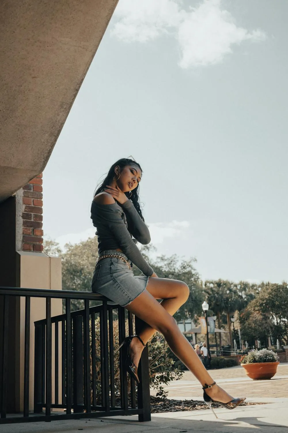 Woman in Skirt Leaning on Balcony Railing Outdoors At Sunset