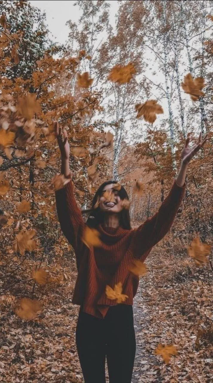 Woman Smiling and Playing with Autumn Leaves Outdoors Image