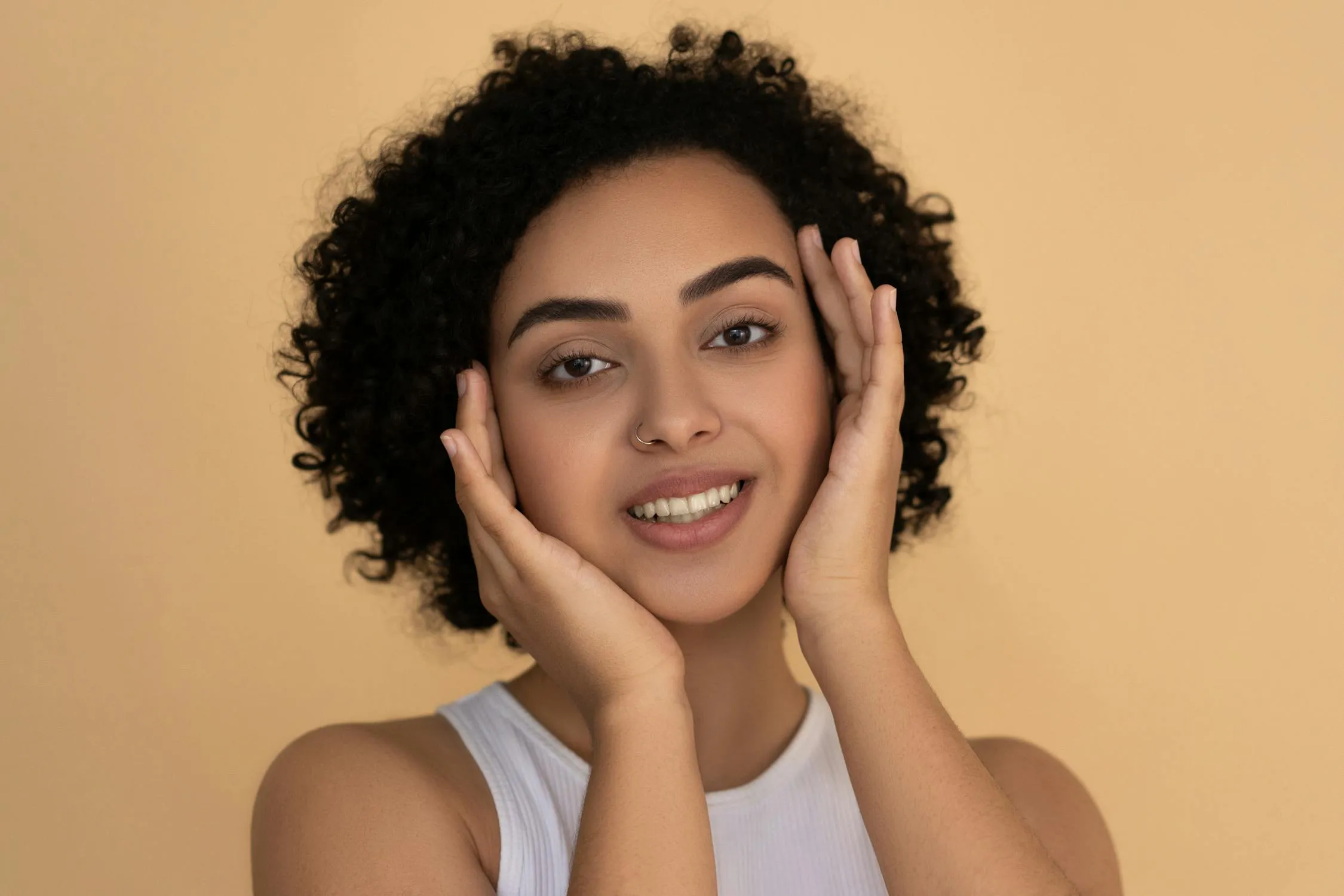 Woman Smiling with Warm Beige Background and Natural Curls