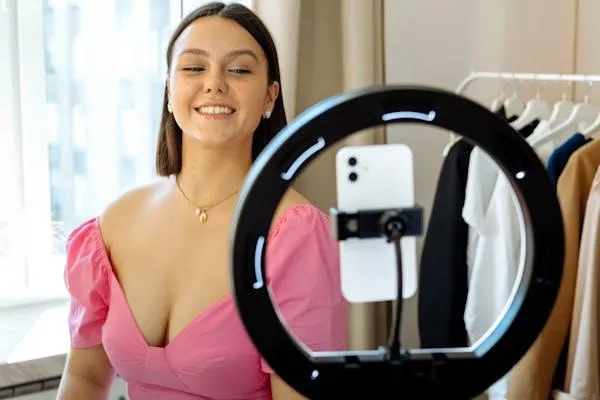 Woman Smiling While Filming Herself with a Ring Light Camera
