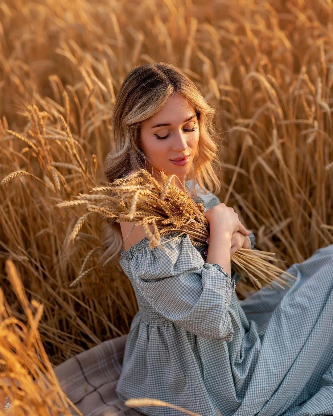 Woman in a Soft Dress Holding Wheat in Golden Sunlight Image