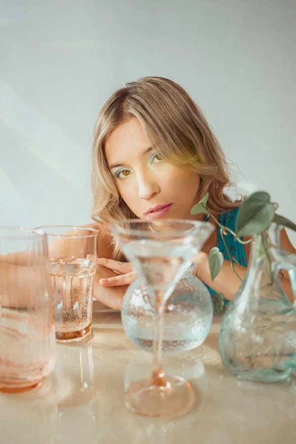 Woman in Soft Lighting with Drinks and Glassware Around Her