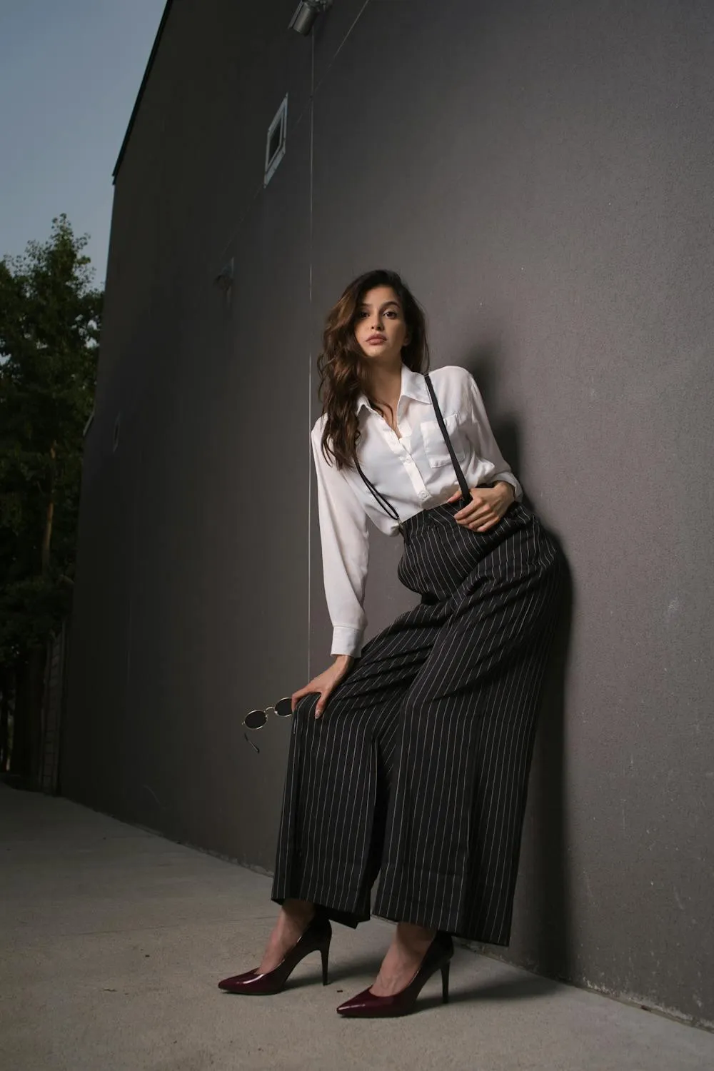 Woman Standing Against a Wall Wearing a Skirt and a Shirt