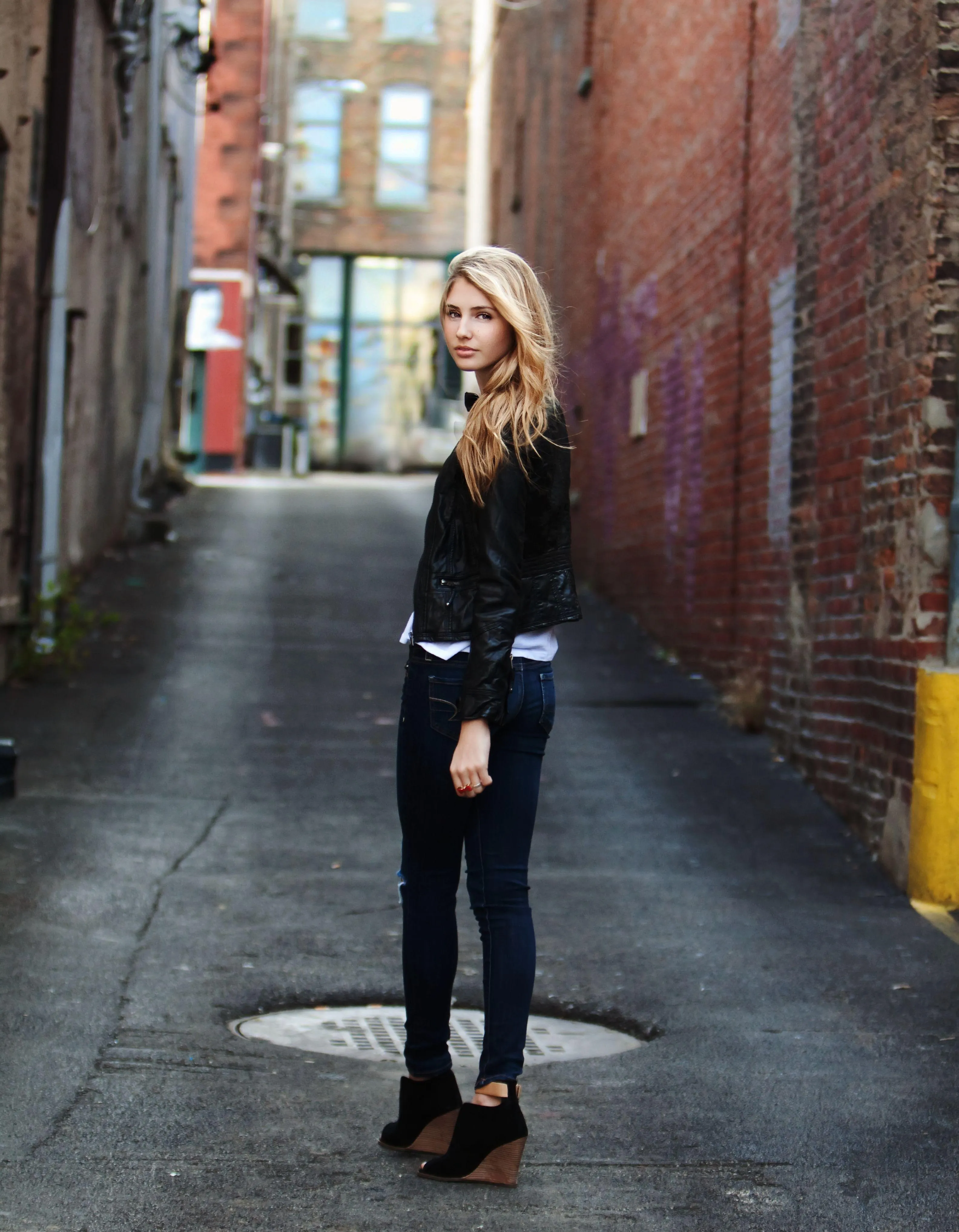 Woman Standing in an Urban Alleyway Wearing a Casual Outfit