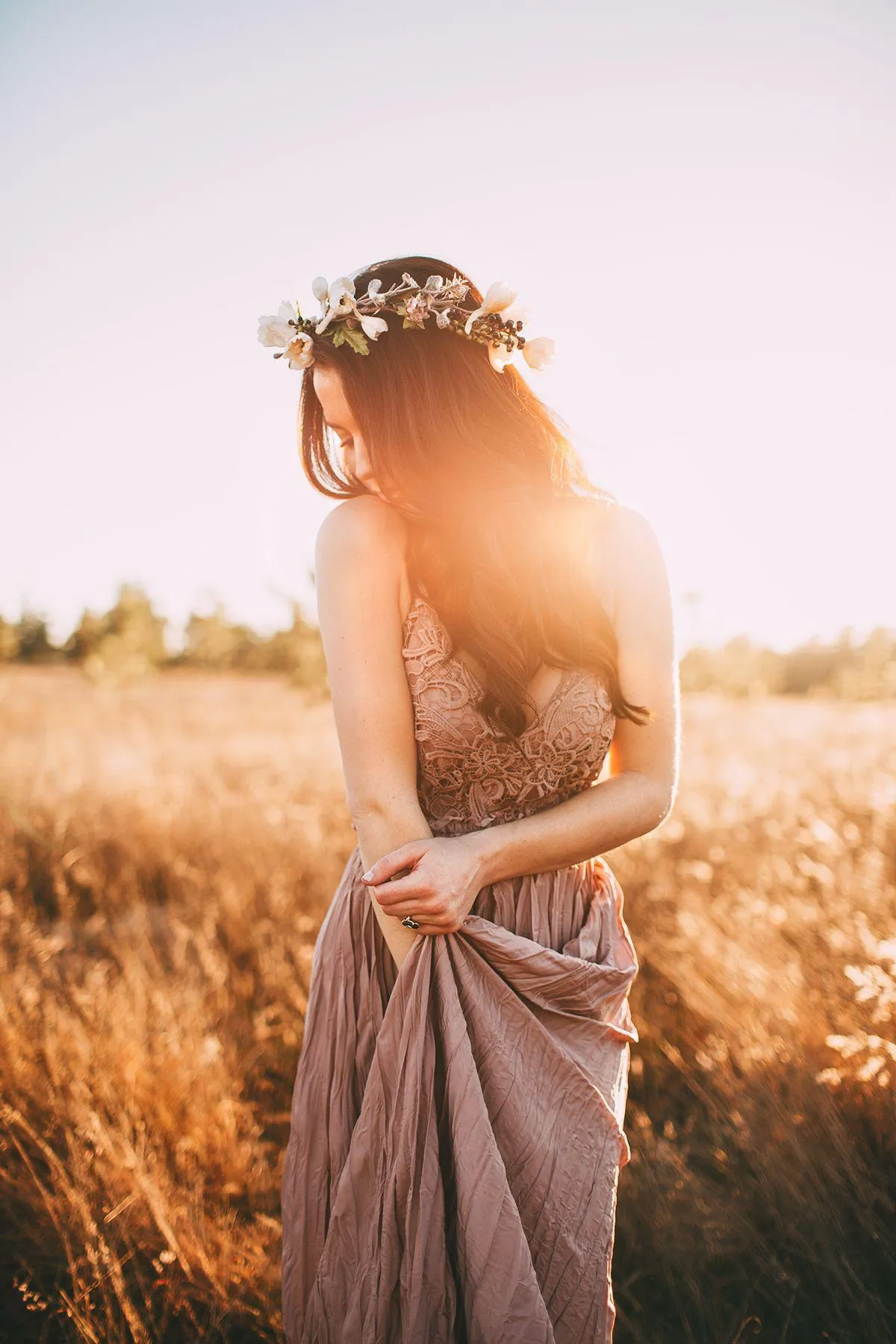 Woman Standing in a Golden Field with the Sun Shining Behind