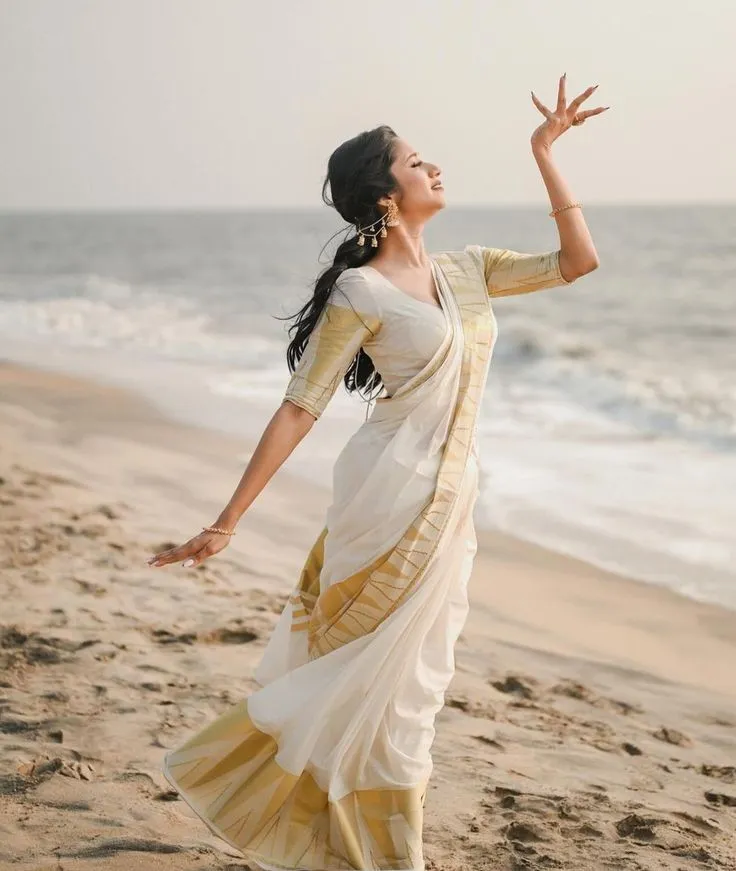 woman standing on the beach with a pose wearing a saree