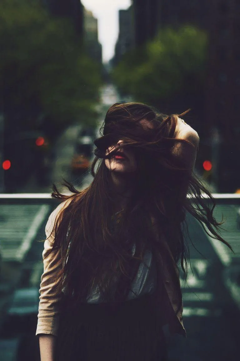 Woman Standing Outdoors with Hair Tied and a City Background
