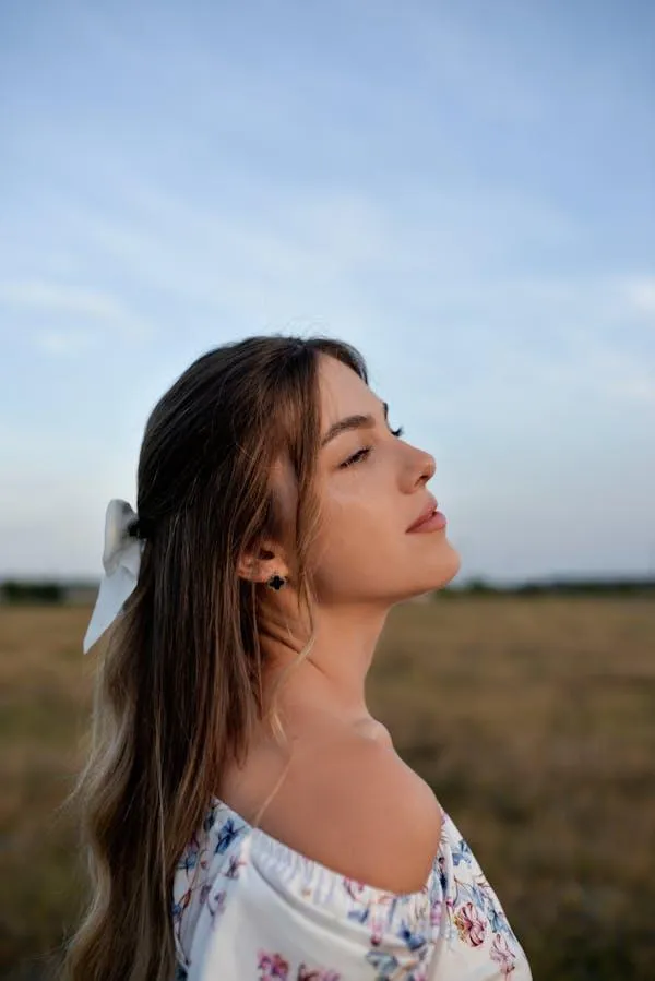 Woman Standing Outdoors with Her Eyes Closed Enjoying Nature