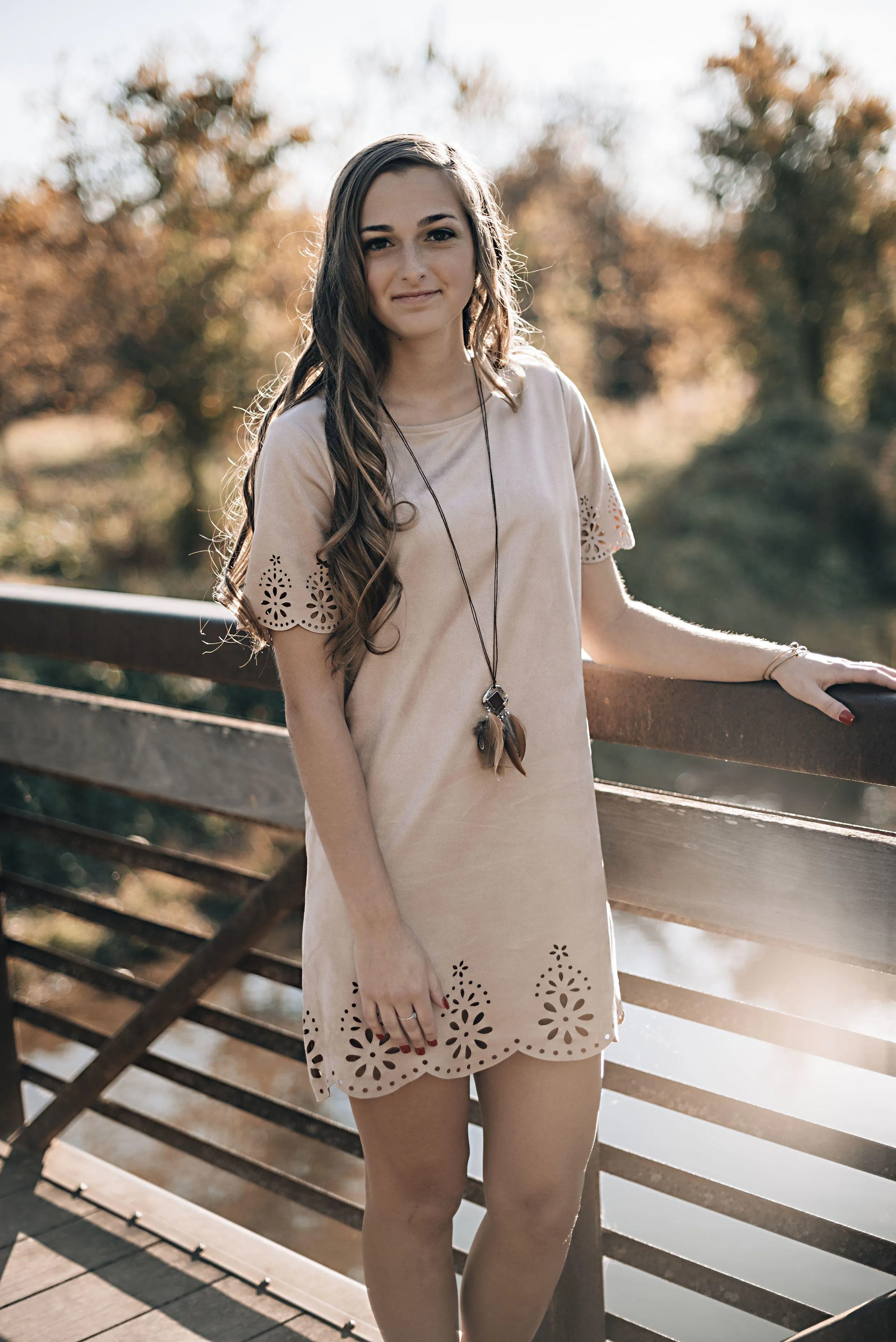Woman Standing by a Railing in a Light Beige Dress Outdoors