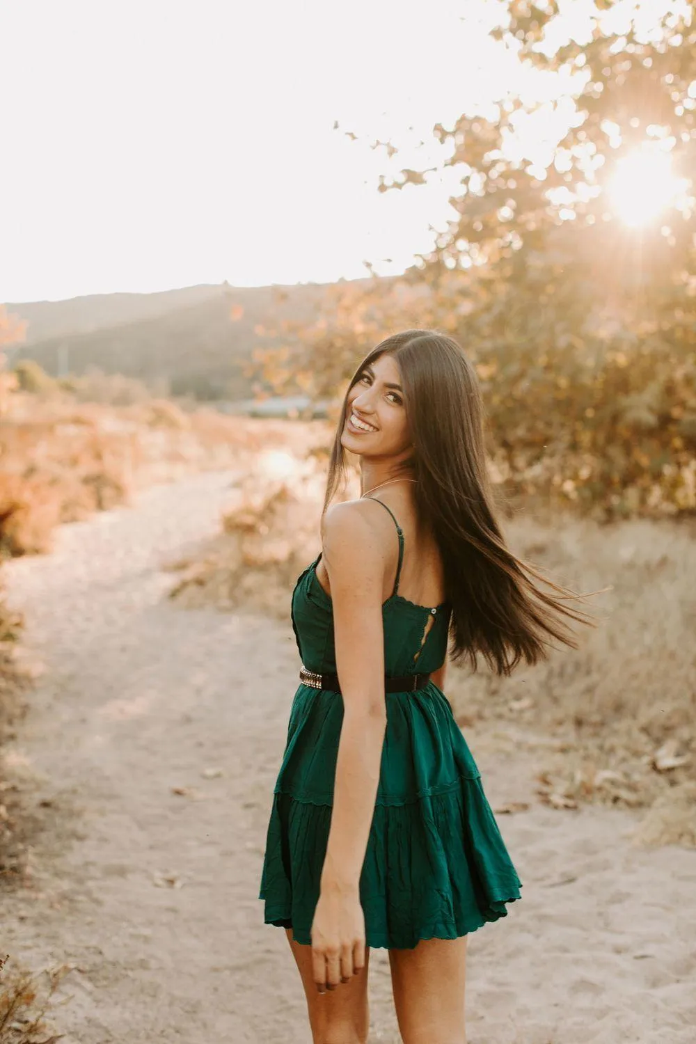 Woman Standing on a Sunny Trail Wearing a Green Dress Image