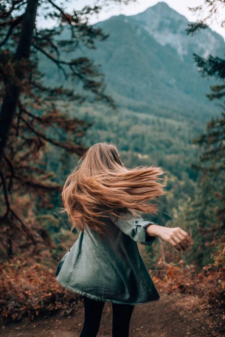 Woman Standing in the Forest Looking Out At the Mountain
