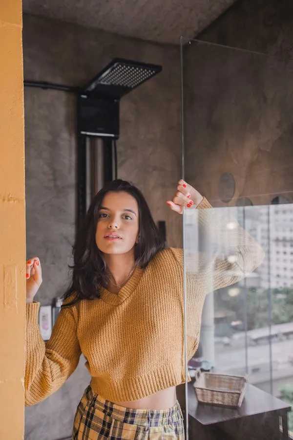 Woman Standing by a Window While Wearing a Brown Sweater