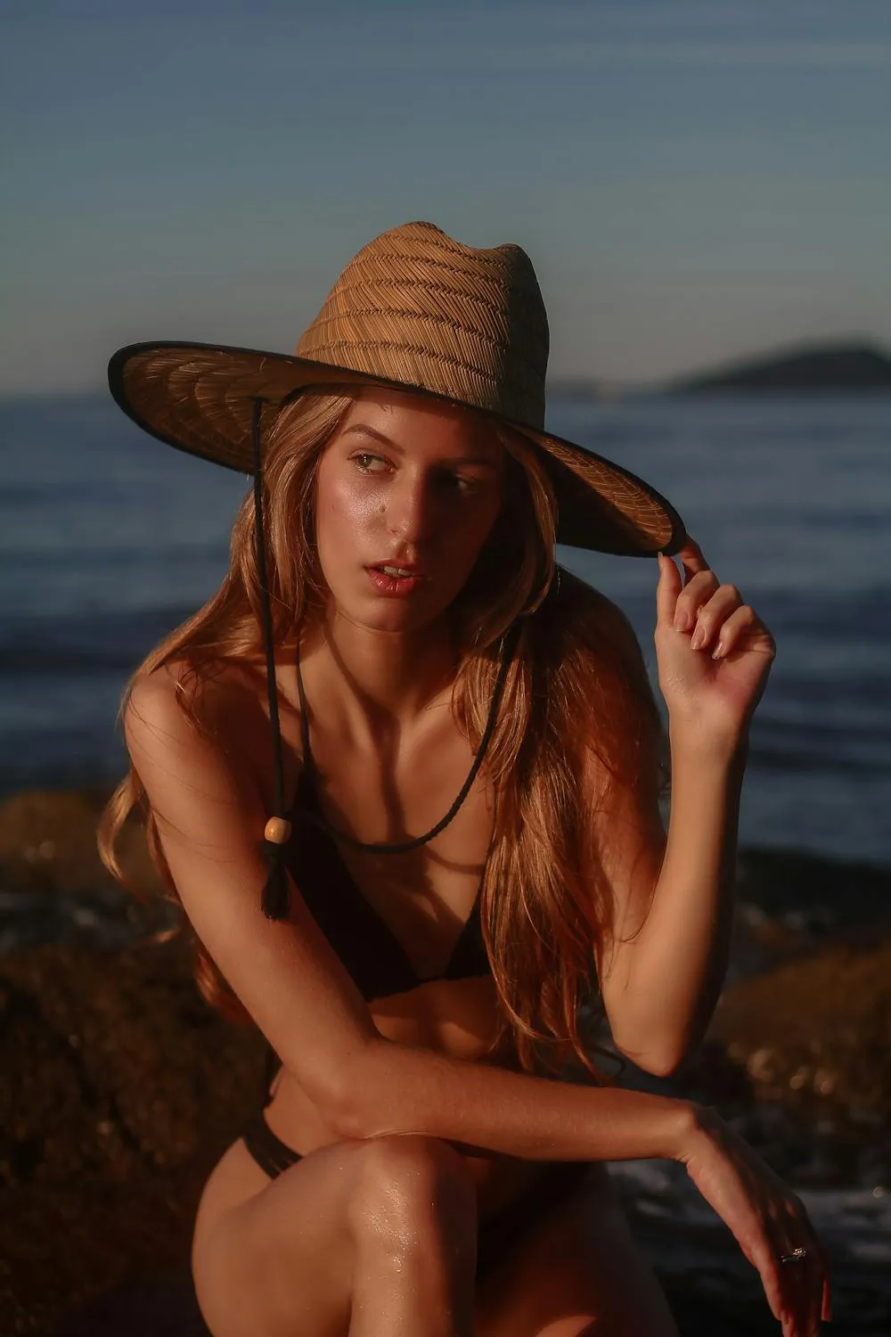 Woman in a Straw Hat Enjoying a Relaxed Moment by the Sea