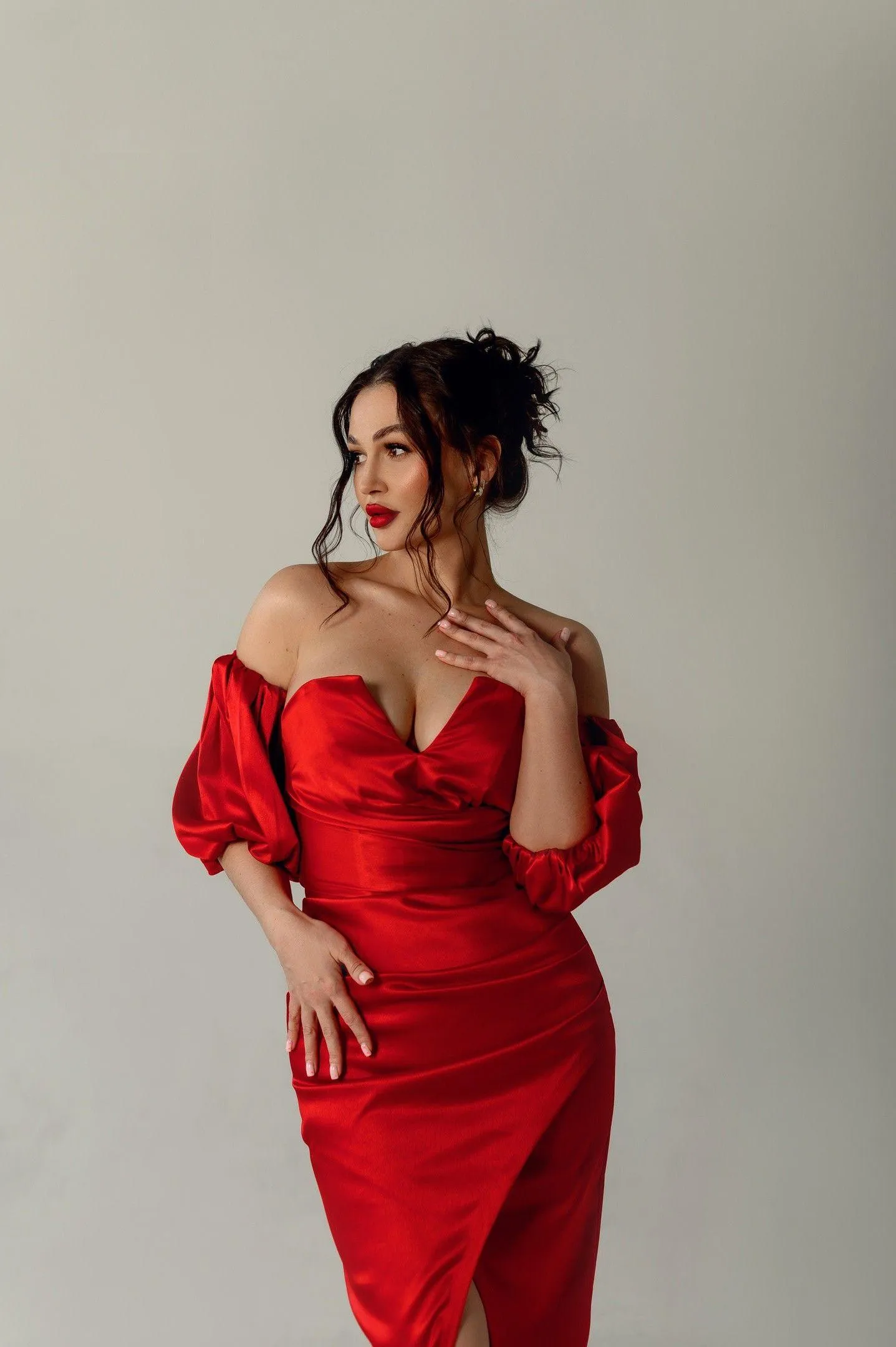 Woman in Striking Red Dress Posing Gracefully Near the Wall
