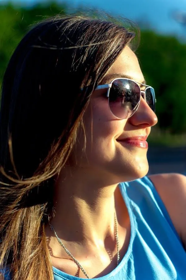 Woman in Sunglasses Smiling While Looking At the Sunlight